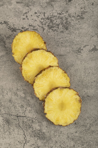 异国风味把美味多汁的菠萝片放在石头表面上新鲜切块柑橘