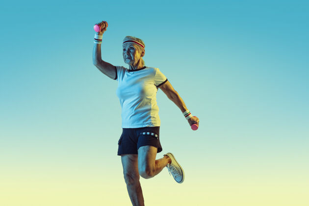 球拍高级女子运动装训练 重量梯度背景 霓虹灯女性模特保持良好的状态运动 活动 运动 健康 自信的概念复制空间健康养老金姿势