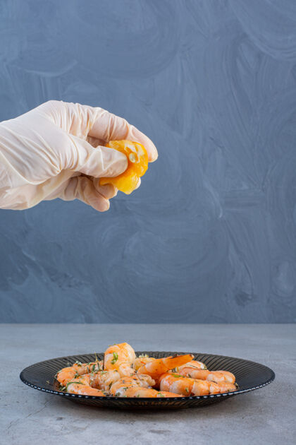 食物用石头做背景 用手在一盘美味的虾里挤柠檬新鲜鱼美味