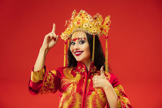女士中国传统的优雅女子在摄影棚的红色背景美丽的女孩穿着民族服装中国新年 优雅 优雅 表演者 表演 舞蹈 女演员 服装的概念惊喜魅力脸