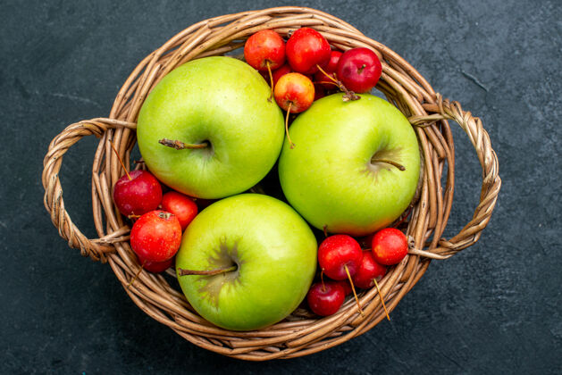 吃苹果顶视图篮子上有水果苹果和甜樱桃 深色书桌上有水果浆果组成的新鲜树水果视野桌子