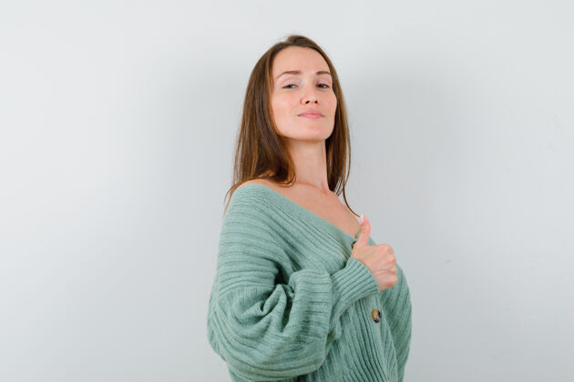 漂亮穿着羊毛开衫的年轻女士竖起大拇指 看上去很自豪 正面视图显示夏天健康