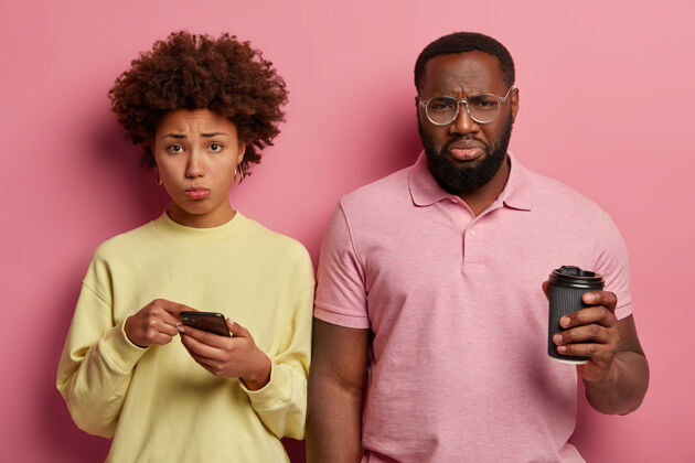 朋友绝望闷闷不乐的美国黑人夫妇在社交网络上读坏消息 喝外卖咖啡 悲伤的女人指着智能手机屏幕失望痛苦闷闷不乐