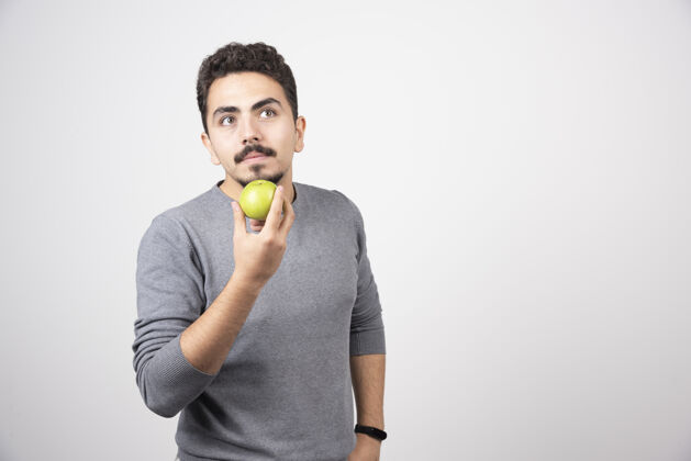 水果年轻人拿着青苹果思考着食物苹果模型