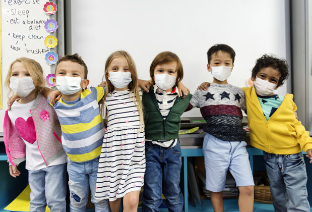 保护幼儿园的孩子戴着口罩在教室里教室儿童群体个人防护设备