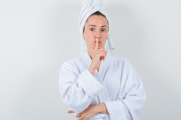 女士身着白色浴衣 毛巾的年轻女士表现出沉默的姿态 看起来很理智 正对着前方漂亮毛巾头发