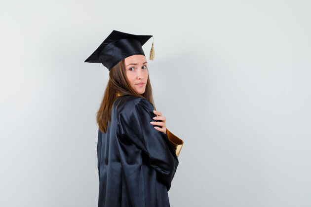 头发年轻的女毕业生穿着学院服 看着镜头摆出迷人的姿势前视图新鲜年轻头部