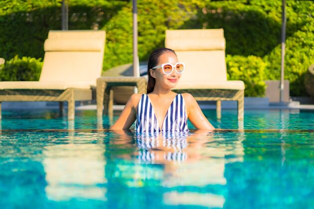 健康肖像美丽的年轻女子放松微笑休闲度假酒店游泳池周围成人热带美容