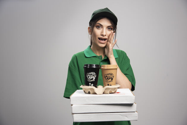 帽子送货员拿着咖啡杯和披萨盒摆姿势承运人工人制服