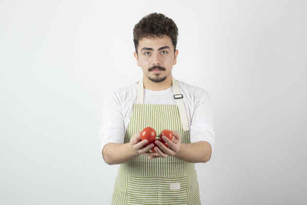 肖像年轻帅哥拿着有机西红柿直视镜头蔬菜西红柿手势