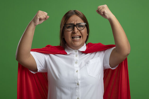 戴愤怒的中年女超人戴着眼镜举起拳头孤立在绿色背景上超级英雄眼镜举起
