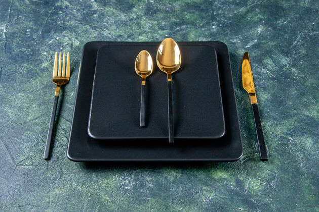 叉子前视图深色盘子 深蓝色背景上有金色的勺子 叉子和刀子刀食物勺子