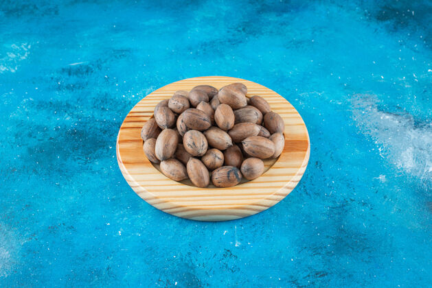 美味把山核桃放在蓝色表面的木板上天然蛋白质美味