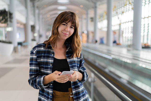 终端女性用智能手机穿过机场科技美丽智能