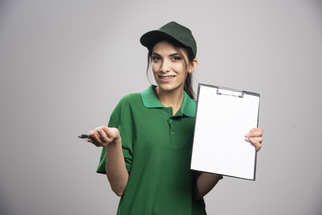 快递穿着绿色制服拿着剪贴板的女送货员雇员剪贴板女孩