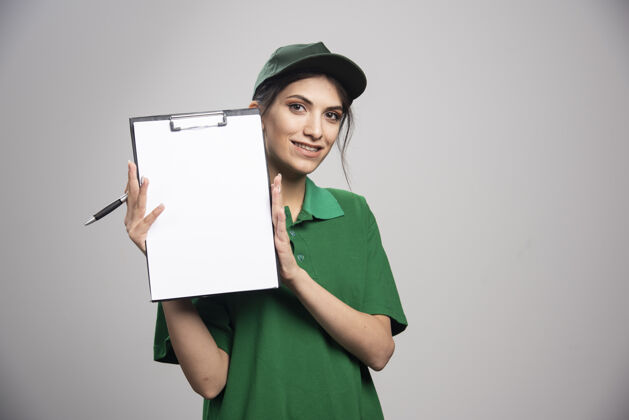工作穿着绿色制服拿着剪贴板的女送货员快递钢笔女人