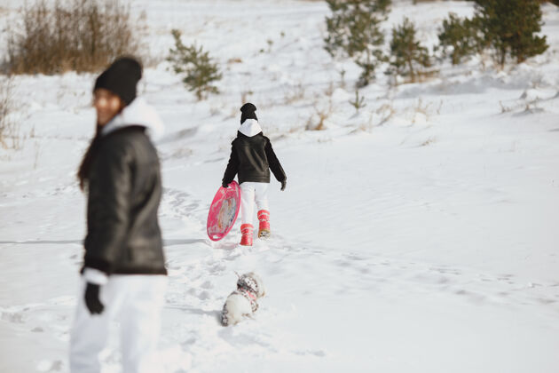 夹克一家人在一起过圣诞节女人和小女孩在森林里人们在散步雪橇小寒冷