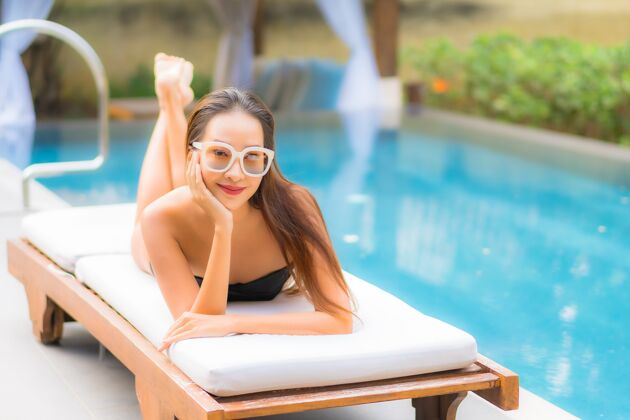 健康美丽的亚洲年轻女子在游泳池里放松的画像度假村健康帽子