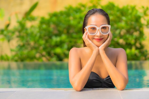 水美丽的亚洲年轻女子在游泳池里放松的画像热带帽子人