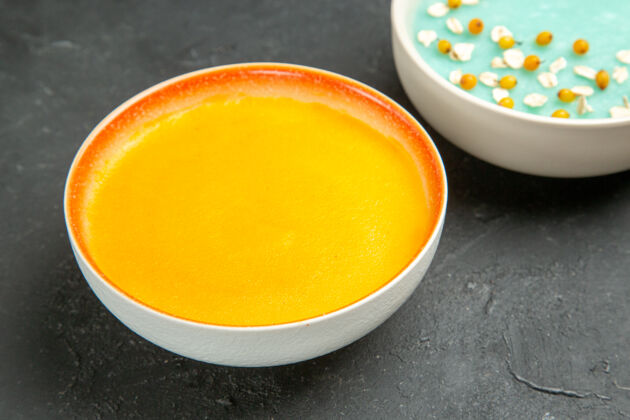 保存正面图美味的南瓜汤在盘子里放在深色的桌子上盘彩色的汤盘子正餐果汁