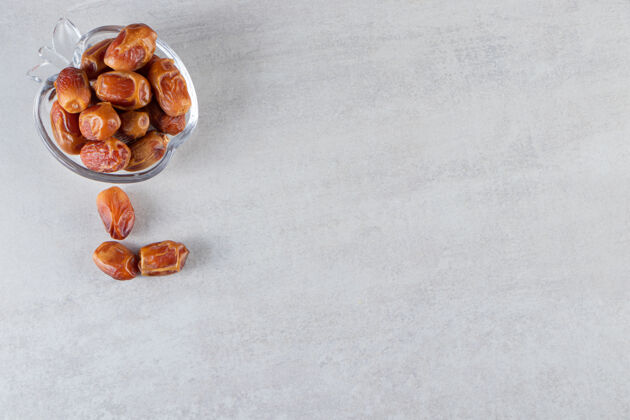 素食放在石桌上的一个玻璃碗 里面装满了麻枣枣水果健康