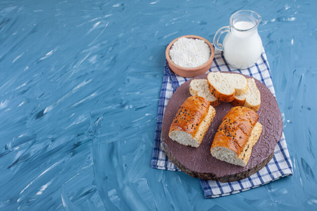 面包一块面包放在煮熟的鸡蛋旁边 一碗面粉放在毛巾上 放在蓝色的桌子上酵母纸板面粉