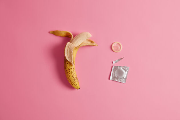 包装安全套在香蕉上测试有效的预防怀孕产品 确保您的安全计划外生育标准尺寸粉色背景香蕉味避孕药节育 避孕香蕉果皮背景
