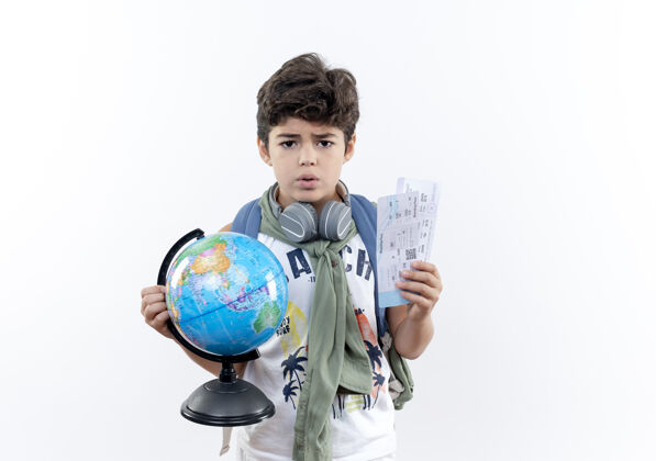 小一个戴着耳机 背着书包 拿着票 把地球仪孤立在白色背景下的小男孩耳机票关心