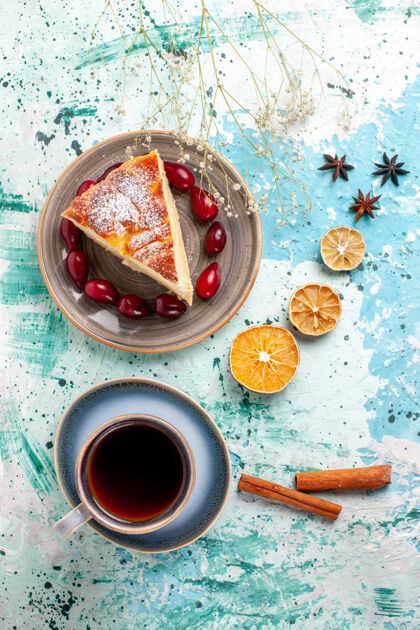 生的顶视图蛋糕片新鲜的红山茱萸和一杯茶在一个蓝色的表面水果蛋糕烤派糖饼干甜切片派容器
