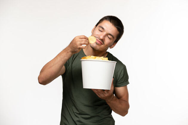 咖啡杯正面图身穿绿色t恤的年轻男子拿着土豆在白墙上吃孤独的电影人咖啡电影杯子