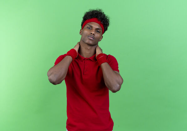 头带自信的年轻美国黑人运动男子戴着头带和腕带保持手在脖子后面隔离绿色背景年轻脖子腕带