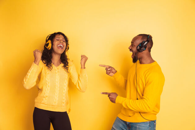 头发年轻感性的非裔美国人男女黄色背景耳机舞蹈休闲