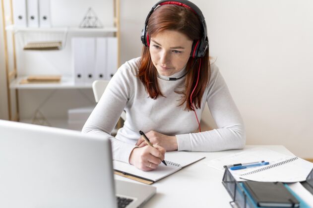 女性上班的女人在打视频电话写作办公桌耳机