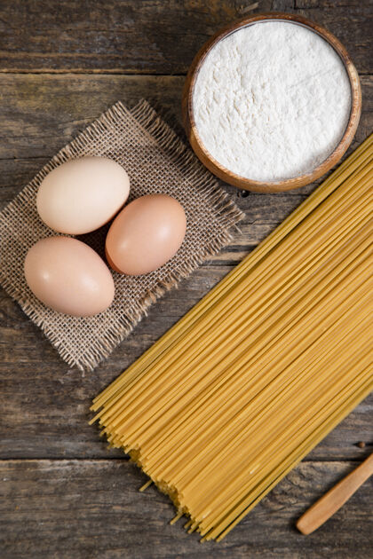 鸡蛋生的意大利面 鸡蛋和一碗胡椒粉放在木头表面高质量的照片长的通心粉烹饪