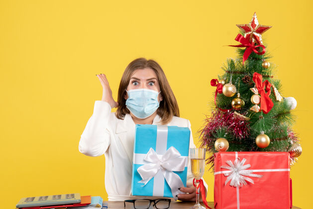 圣诞节正面图：戴着无菌口罩的女医生带着礼物人面具颜色