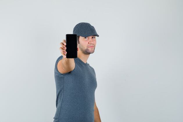 远视年轻男子戴着t恤帽展示手机 看上去很自信电脑网络摄像头显示小
