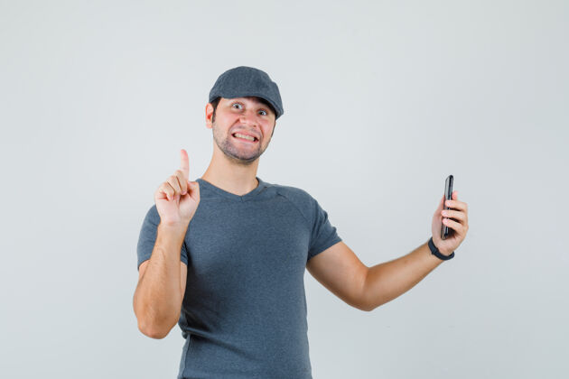 手机年轻男子手持手机 戴着t恤帽 面带微笑幼儿速度训练帽子