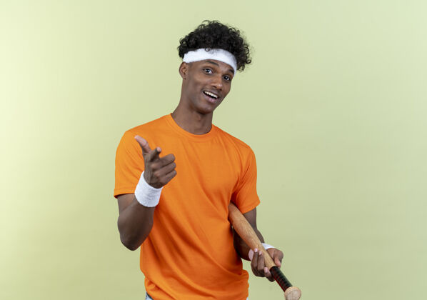 非裔美国人快乐的年轻美国黑人运动男子戴着头带和手环举行位 并显示您的姿态孤立的绿色背景显示年轻手势