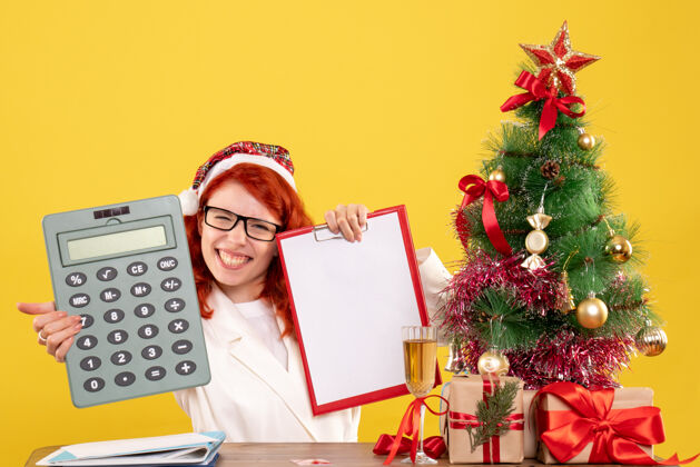 礼物前视图女医生拿着计算器围着圣诞礼物和圣诞树周围树节日