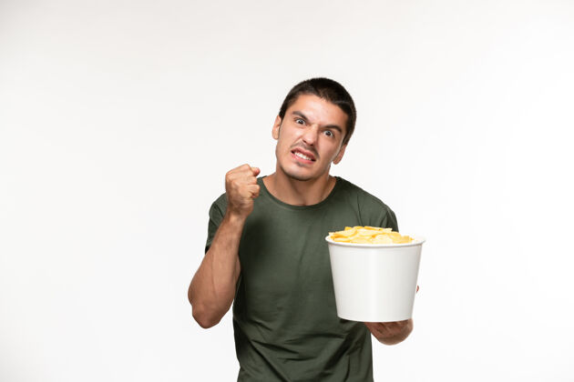 年轻男性正面图身穿绿色t恤的年轻男子手持土豆cips在浅白的墙上孤独的电影人电影咖啡电影