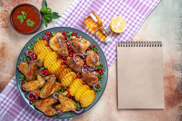 美味顶视图鸡肉鸡翅土豆柠檬油在桌布旁边的灰色笔记本油餐厅食物