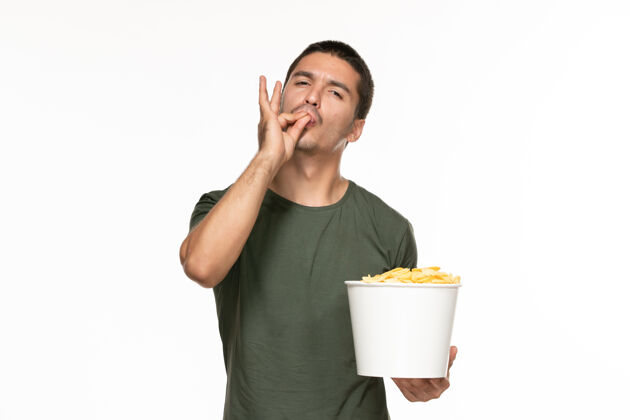 年轻男性正面图身穿绿色t恤的年轻男子拿着篮子和土豆在白色的墙上孤独地享受电影成人观点篮子