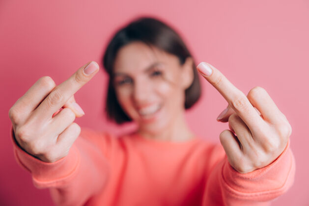 成人女人穿着休闲毛衣在背景上露出中指做不好的表情 挑衅和粗鲁的态度中指手特写