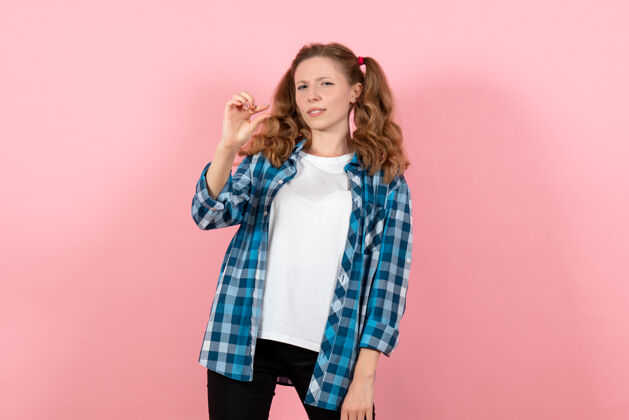 青年正面图身着蓝色格子衬衫的年轻女性在粉色背景上摆姿势青春情感女孩模特时尚小子微笑衬衫漂亮