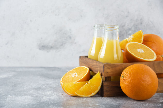 橙子石头桌上放着一个木制的旧盒子 里面装满了桔子和玻璃罐的果汁美味异国情调热带