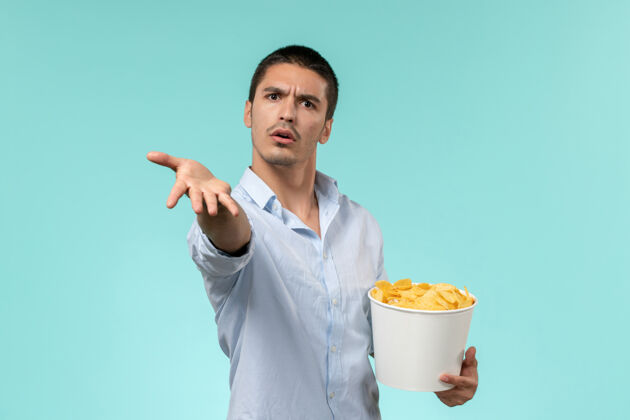 电影正面图年轻人拿着篮子和土豆在蓝墙上吃着看电影孤独的遥远的电影院年轻人男人成人