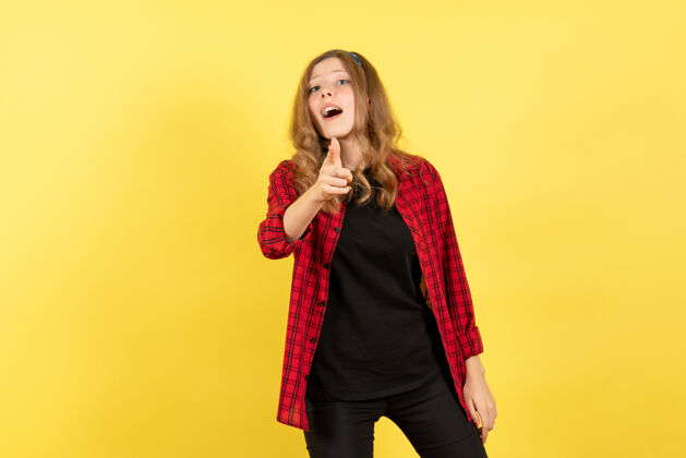 成人正面图身着红色格子衬衫的年轻女性在黄色背景上展示她的情感人类色彩情感模特时尚年轻女性秀衬衫