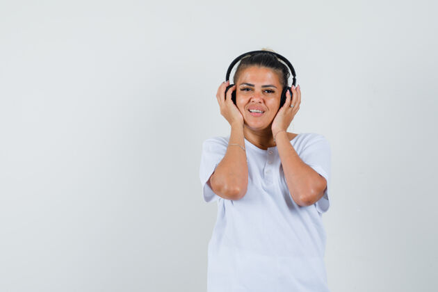 休闲穿t恤的年轻女士戴着耳机听音乐优雅兴奋黑发