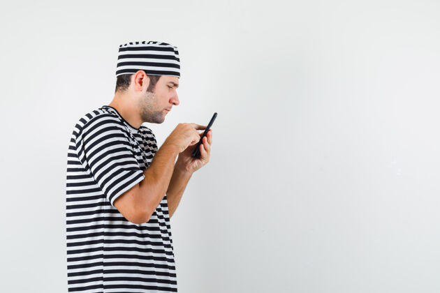 人年轻男性穿着t恤 戴着帽子 用手机 看起来很专注肖像思想电话