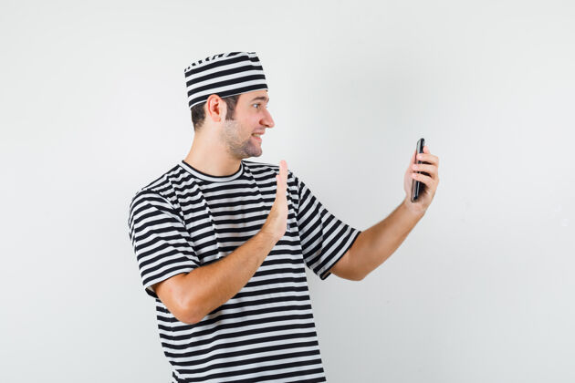 休闲年轻的男性穿着t恤 戴着帽子在视频通话中挥舞着手 看上去很快乐 正面视图挥手胡子人